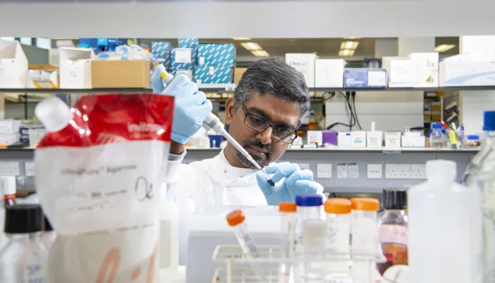 Researcher in a lab, pipetting.