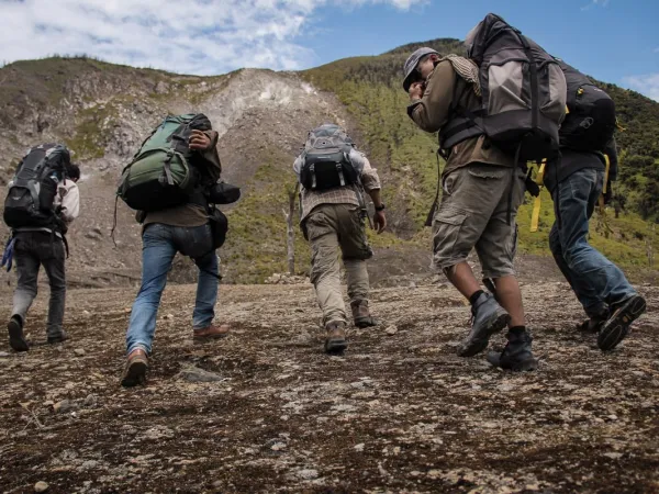 A group of people in hiking gear walking up some rough terrain