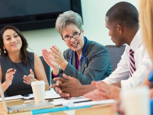 A group of doctors are having a discussion whilst sitting around a table.