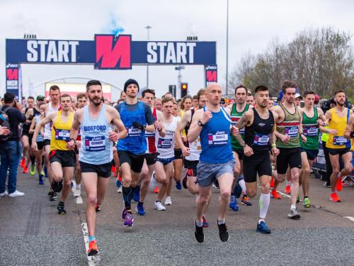 A large group of runners going past the starting line of the Manchester Marathon.