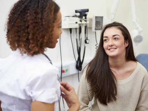 A smiling young woman talking to a female doctor.