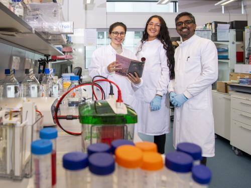 Researchers smiling in a lab, wearing white lab coats.