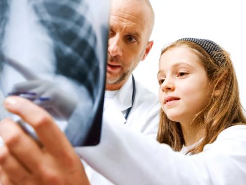 A doctor and a young girl are looking at an x-ray.