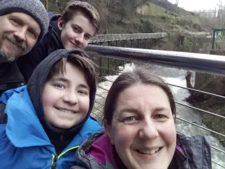  A family selfie taken above a river features two young boys, a woman, and a man.