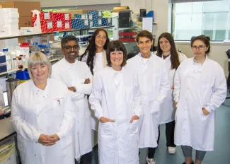 A group of researchers in a research lab is all wearing white lab coats.