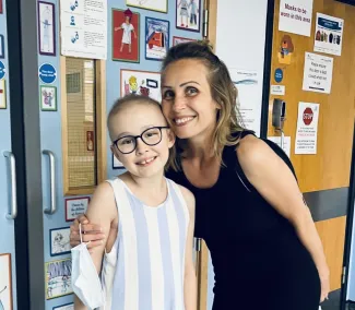 A mother has her arm around her daughter, who has little hair in the hospital.