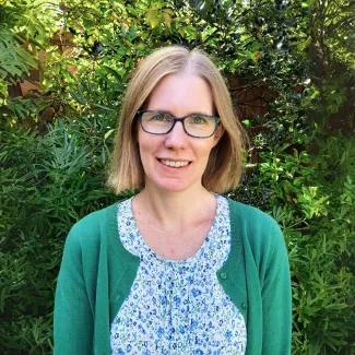 Susie outdoors, smiling at the camera in a green cardigan and floral blouse.