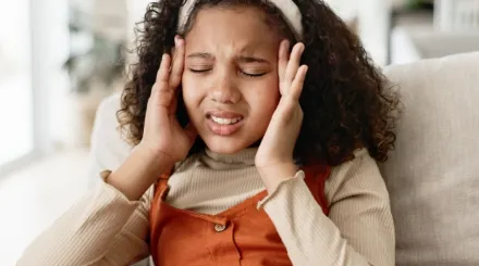 A young girl holding the sides of her head in pain