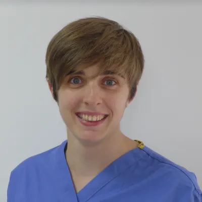 Dr Jess Morgan wearing blue scrubs and smiling at the camera.