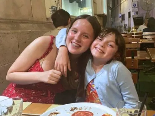 Ellie and her younger sister Hattie hugging at a restaurant.