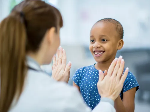 A girl with cancer high fiving a female doctor. 