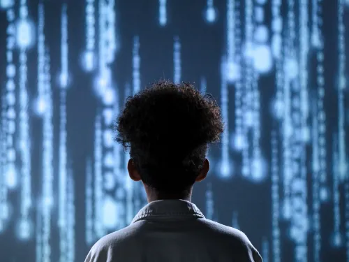 A child stood facing a screen with lines of code.