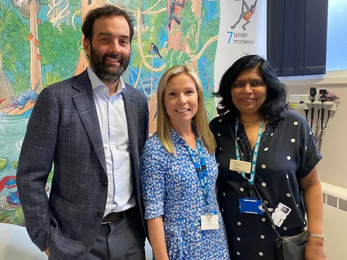 Henry with Paula and Mary in a hospital room, smiling at the camera and wearing NHS lanyards.