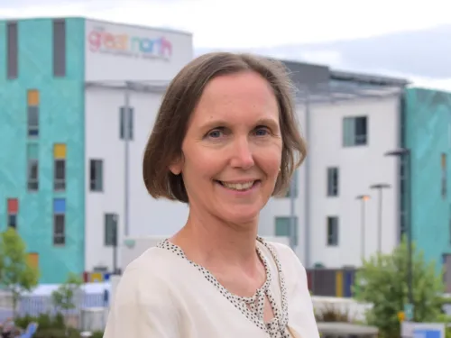 Deborah smiling at the camera. She has short brown hair and is wearing a light coloured blouse.