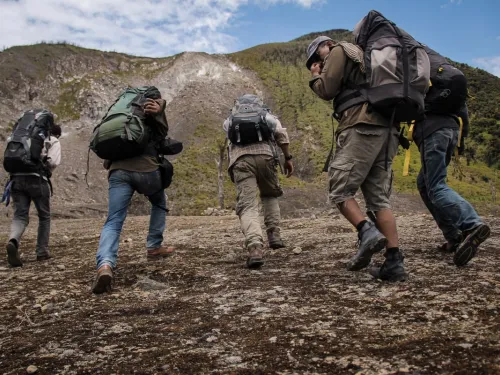 A group of people in hiking gear walking up some rough terrain