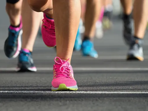 The legs and feet of runners running on a road