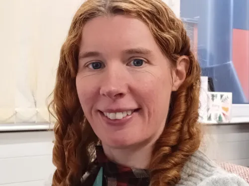 Maddi smiling at the camera with her red hair in curls.