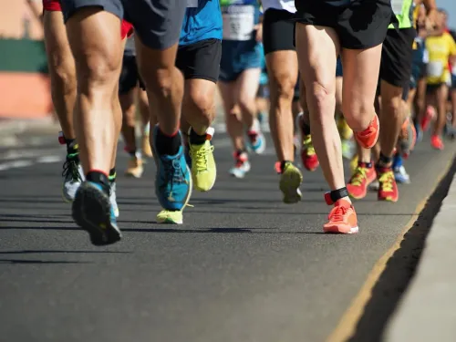 A view of the legs and trainers of people running on a paved road.