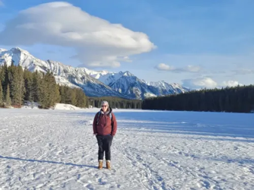 Vicky walking in a snowfield in Canada, with mountains in the background. She is wearing a burgundy coat and brown boots.