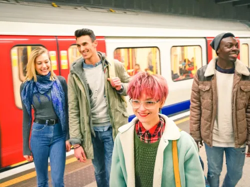 A group of smiling young people getting off a tube train