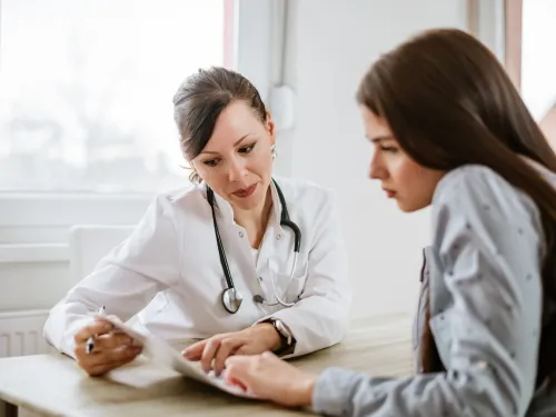 A young woman sitting a desk talking through results with a doctor