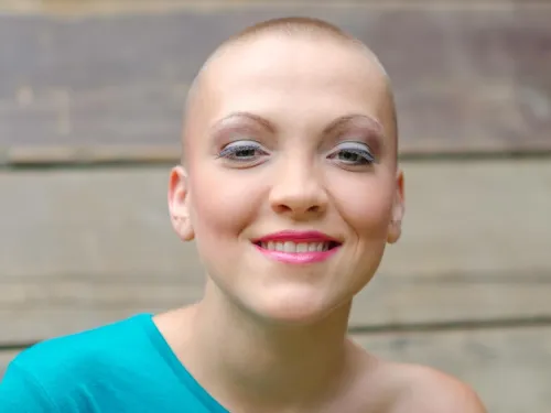 A young smiling woman with a shaved head.