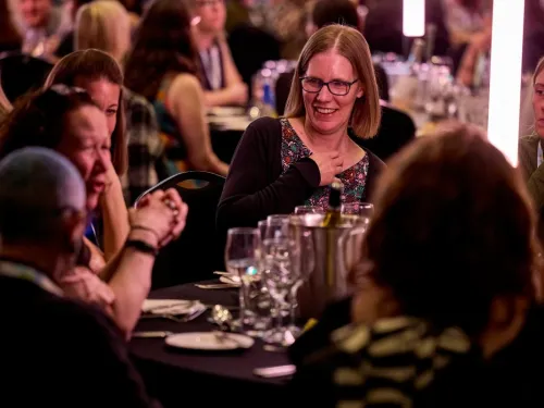 People sitting around a dinner table, smiling and chatting, at the CCLG annual conference.