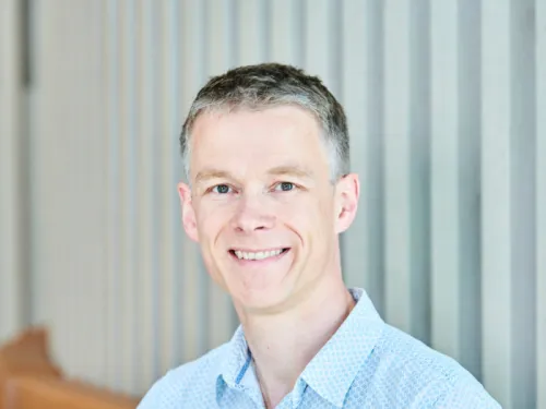 man in a blue shirt with short hair smiling at camera