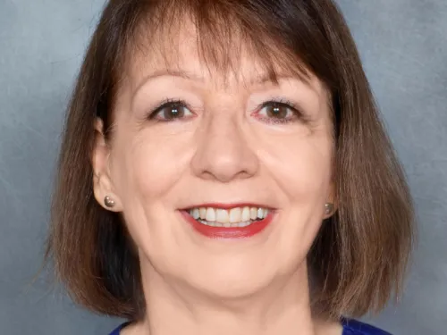 A nurse with a brown bob and small earrings smiling at the camera 